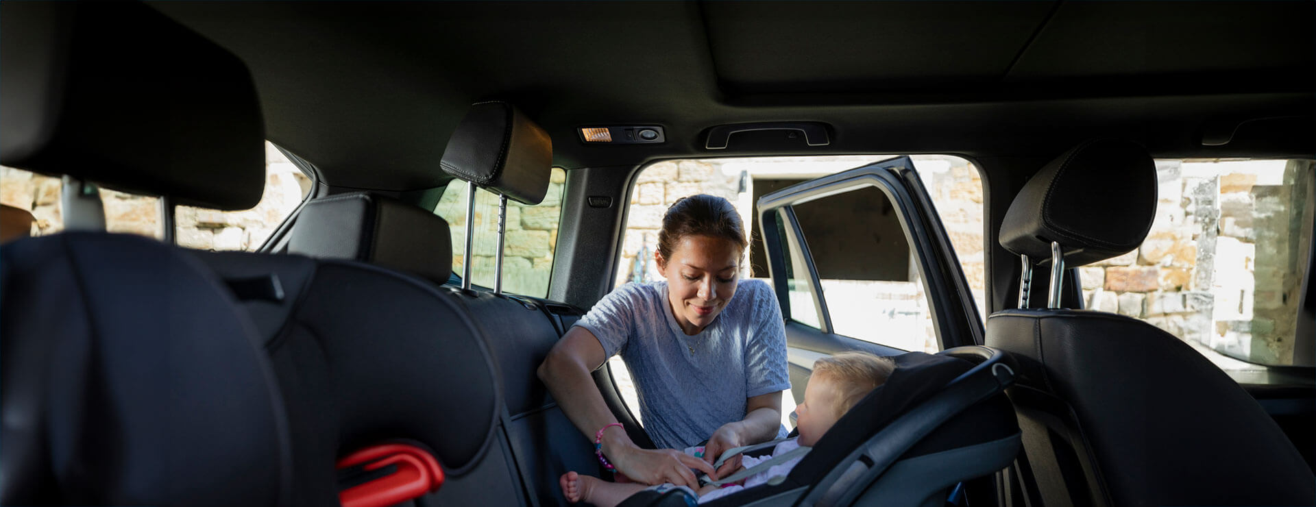 A mother practices car safety by strapping a child into a car seat