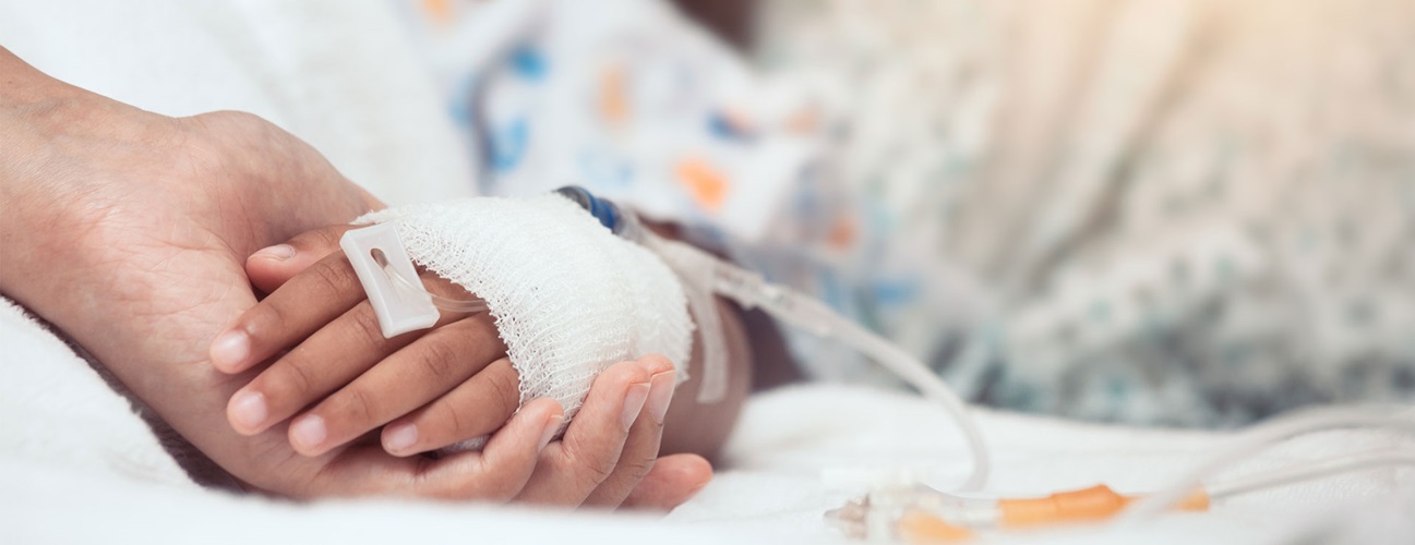 Parent holds child's hand in hospital