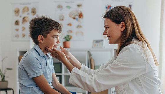 A doctor observes the face of a young patient