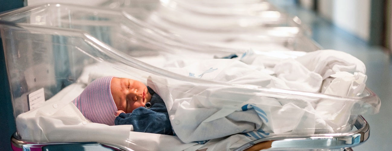 An infant rests in a hospital bassinet