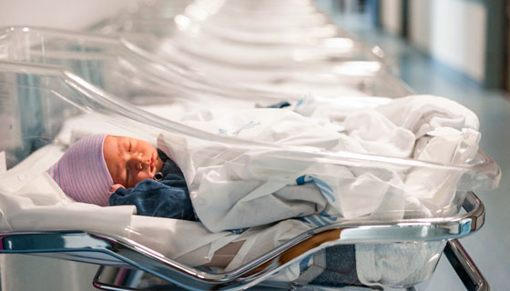 An infant rests in a hospital bassinet