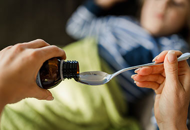 adult measures out the correct medicine dosage for a child
