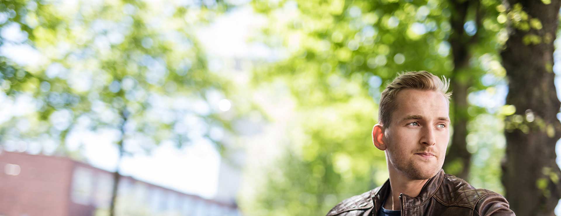 A young man looks thoughtfully into the distance.