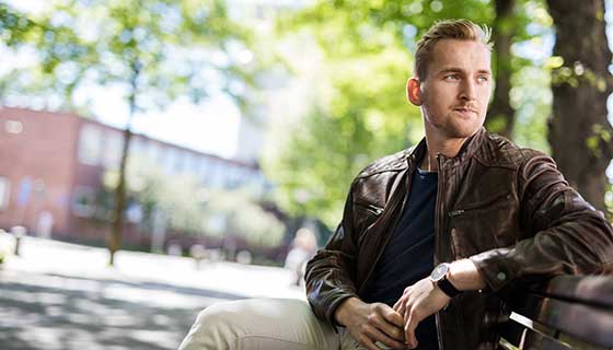 A young man looks thoughtfully into the distance.