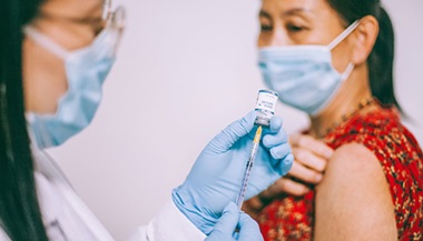 a health care provider prepares a vaccine for a mature woman