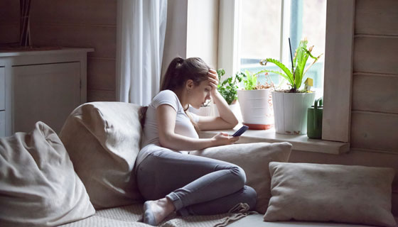 A young woman looks solemnly at her phone