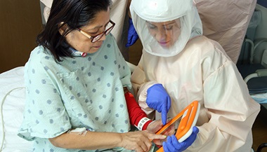 A specialist wearing PPE works with a patient in the hospital.