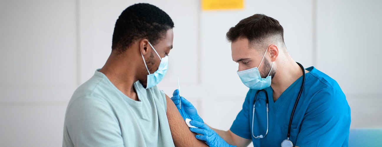 A provider vaccinates a patient in their arm.