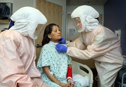 Specialists wearing PPE examine a patient's throat.