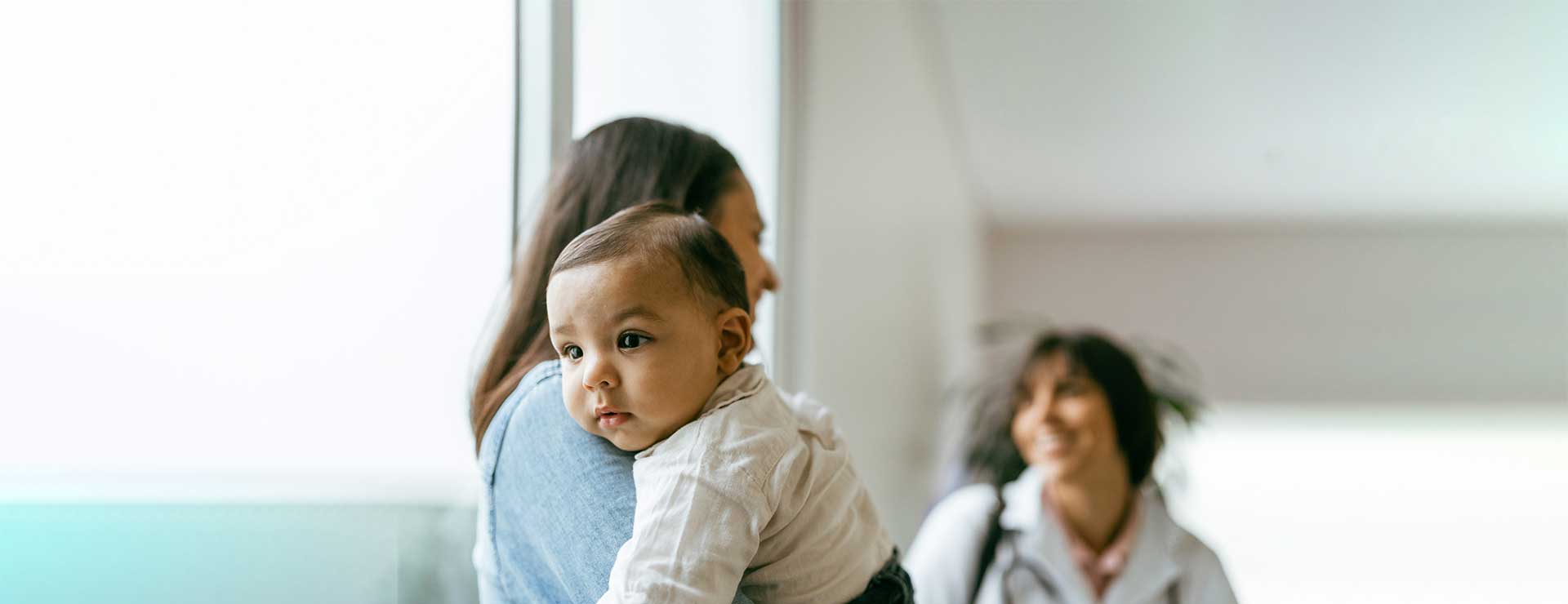 parent holding a baby talking to a doctor