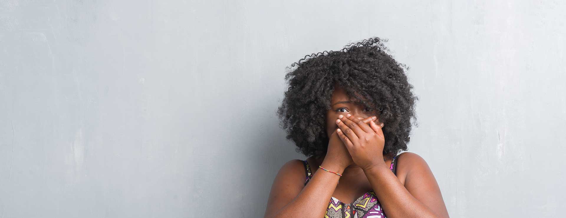 A woman covers her mouth in embarassment.