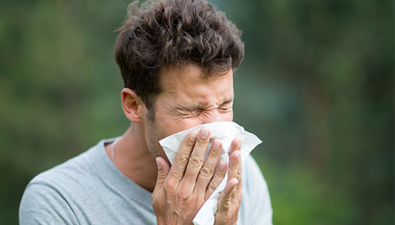 man sneezing into a tissue