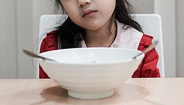 child sits in front of empty bowl