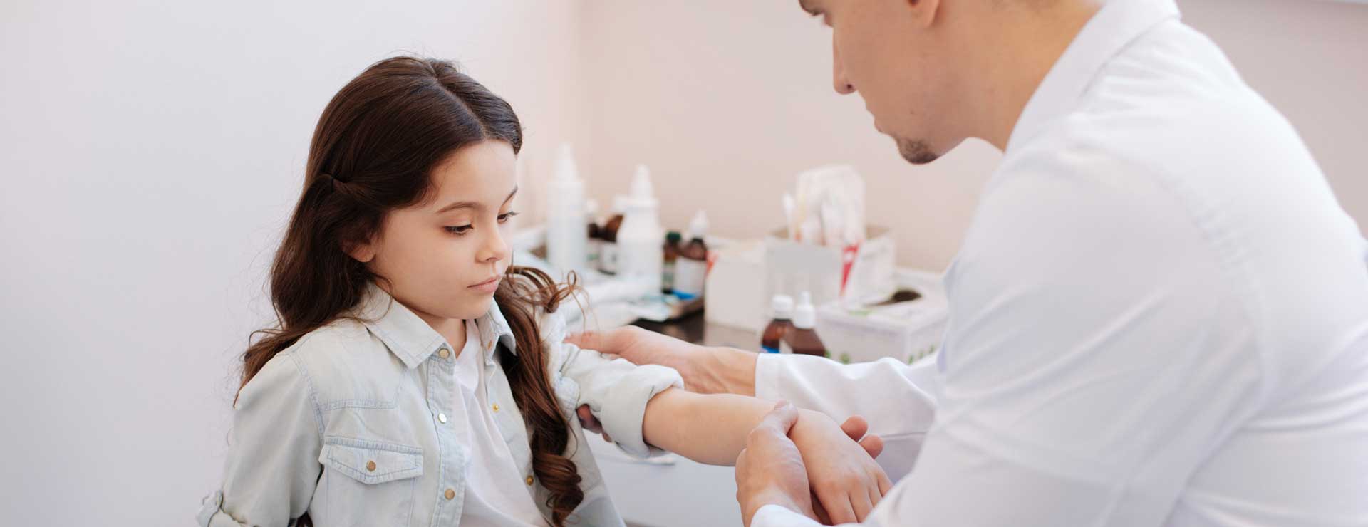 Pediatric doctor examining patient's elbow