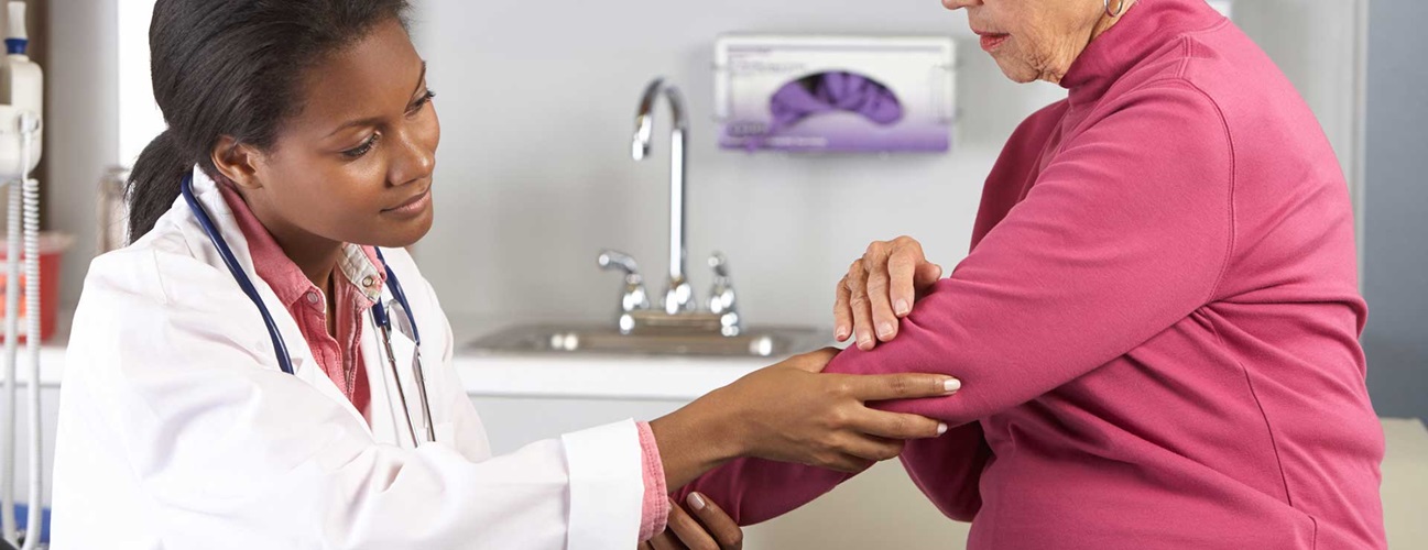 Doctor examining older patient's elbow
