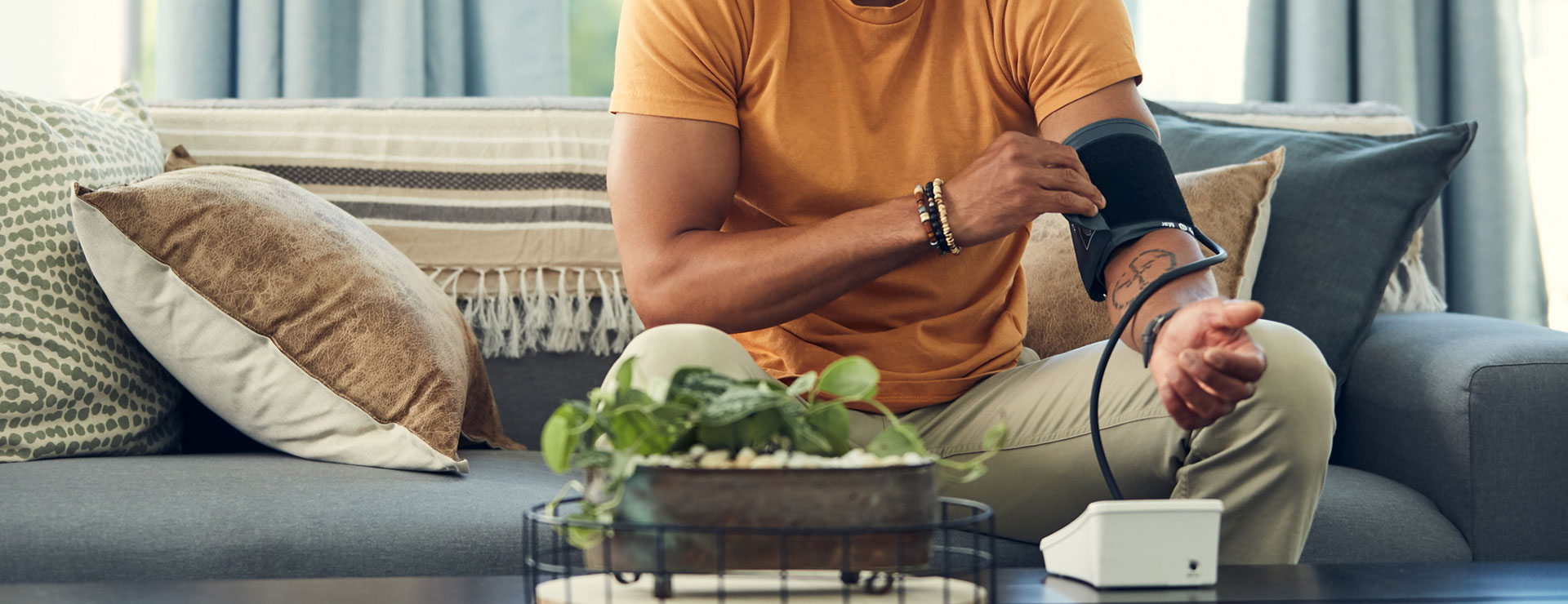 a man takes his own blood pressure at home on his couch
