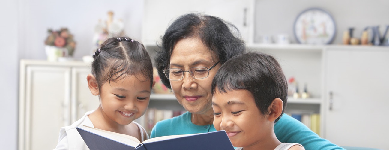 A grandmother with glasses reads to her grandchildren