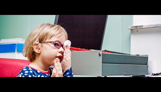 A young girl taking a vison test by covering one eye