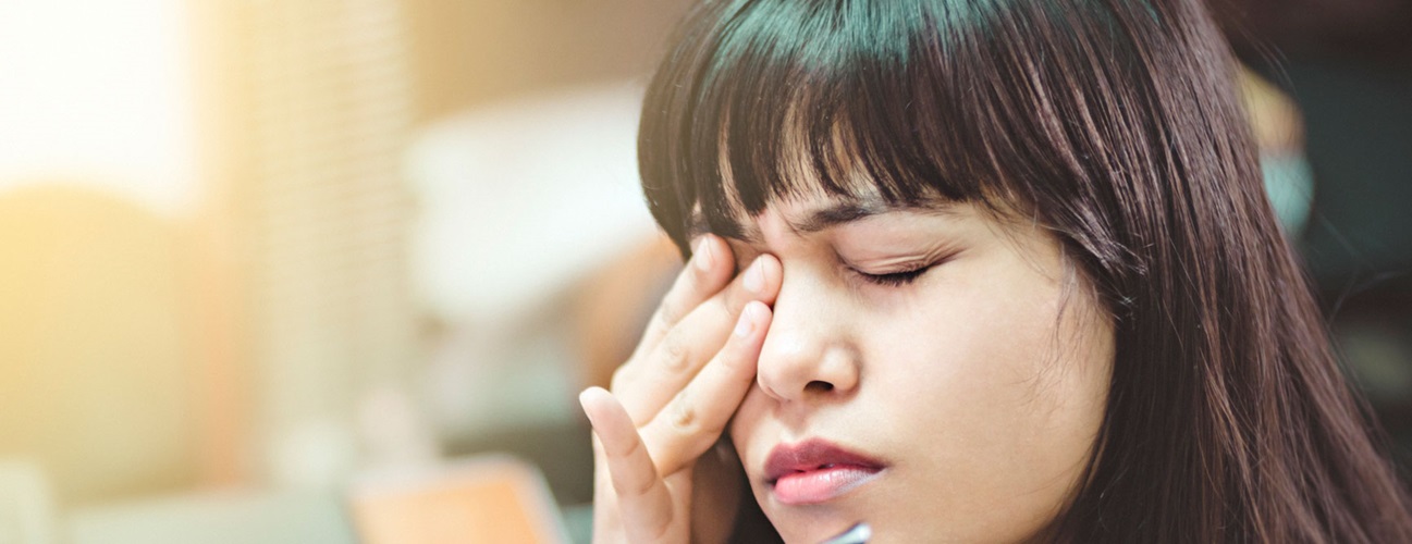 A young woman rubs her irritated right eye