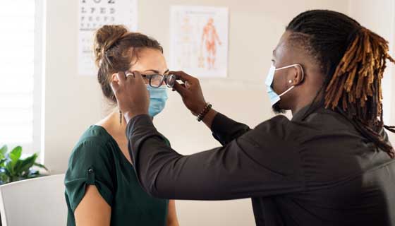 A young woman is fitted for eye glasses by an optometrist.