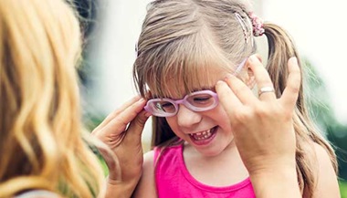 A mother adjusts her daughter's glasses.