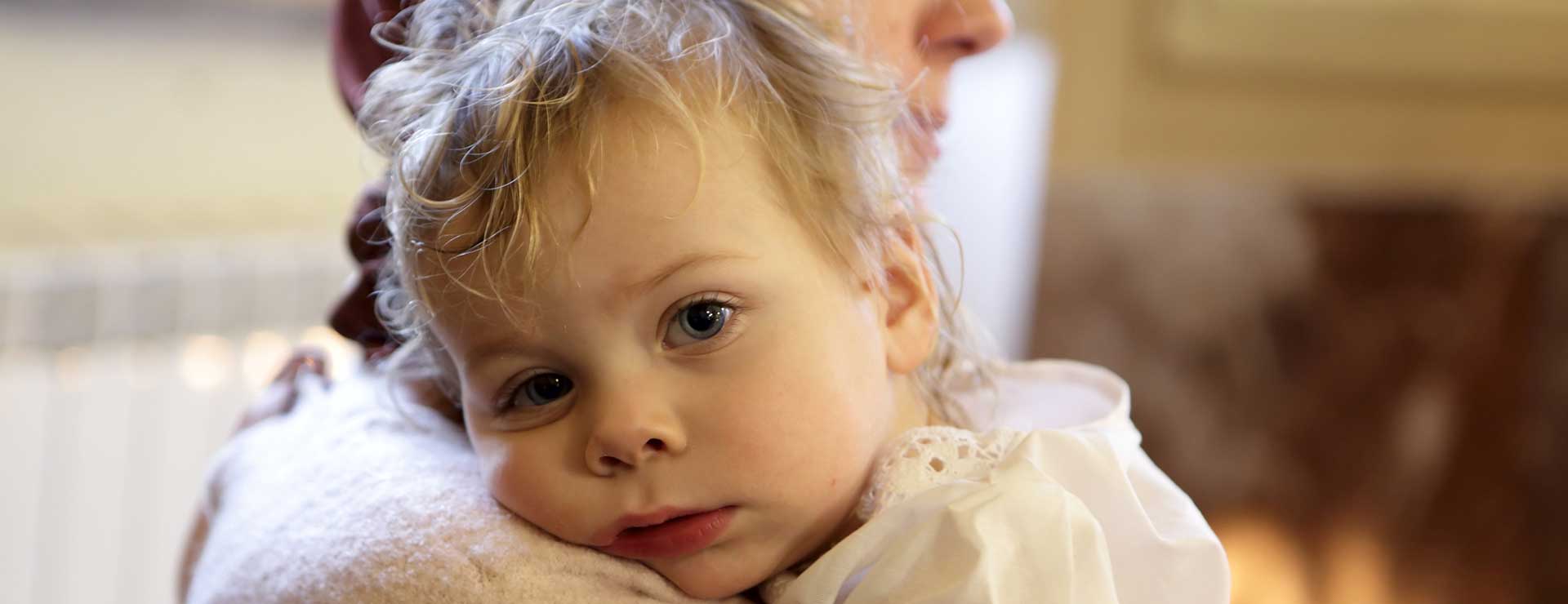 A child rests upon their mother's shoulder.