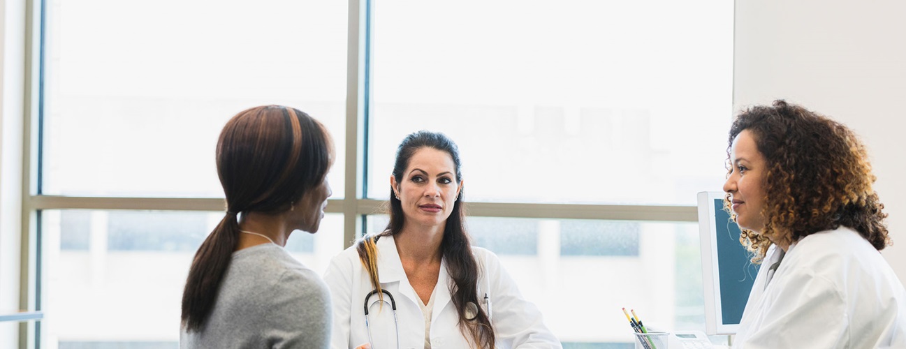 Two doctors speaking with an adult patient during a consultation