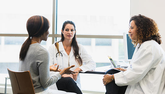 Two doctors consulting with a patient in a sunny room