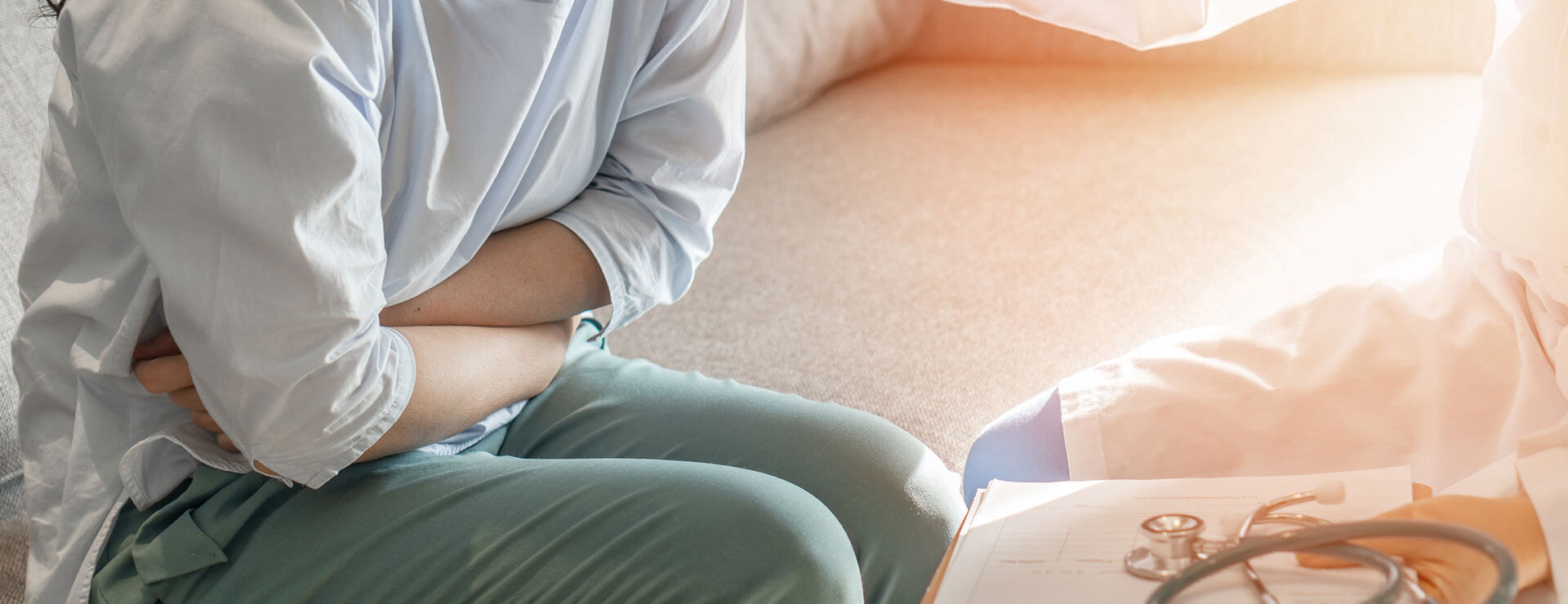 person at doctors office crosses arms over lower abdomen