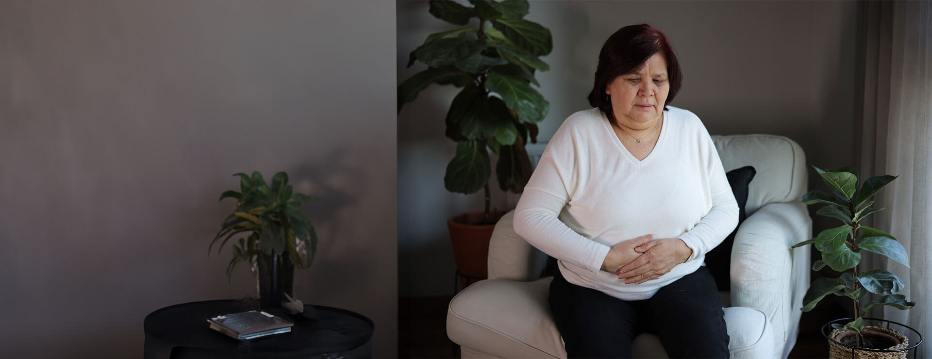 older woman with hands on abdomen