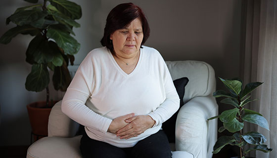 older woman with hands on abdomen
