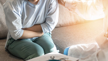 Woman holding her stomach as she experiences abdominal pain