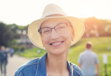 Bald woman smiling and wearing a sun hat