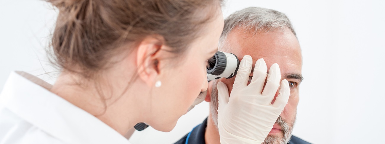 doctor checking patient's skin with magnifier
