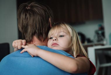 Father comforting his daughter with a hug while she is feeling unwell