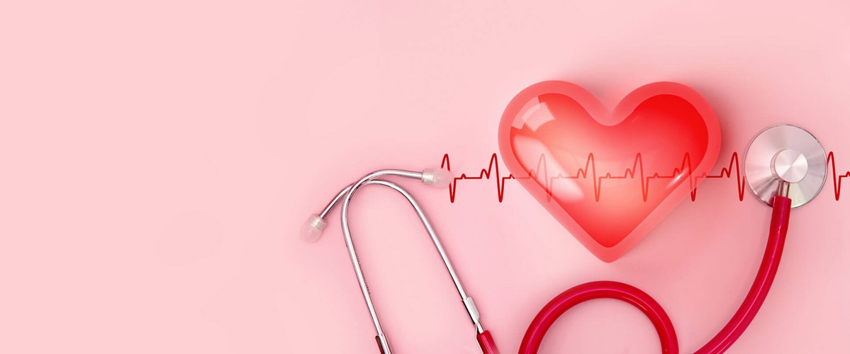 plastic heart and stethoscope against pink background