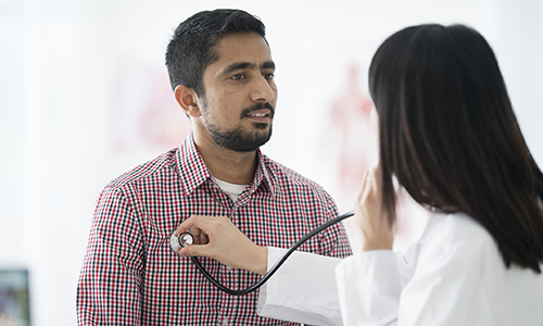 myocarditis - doctor listening to male patient's chest with stethoscope