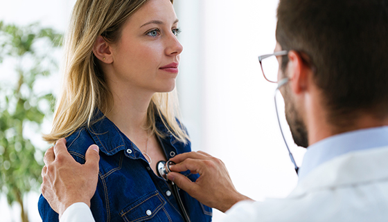 myocarditis - doctor listening to young female patient's chest with stethoscope