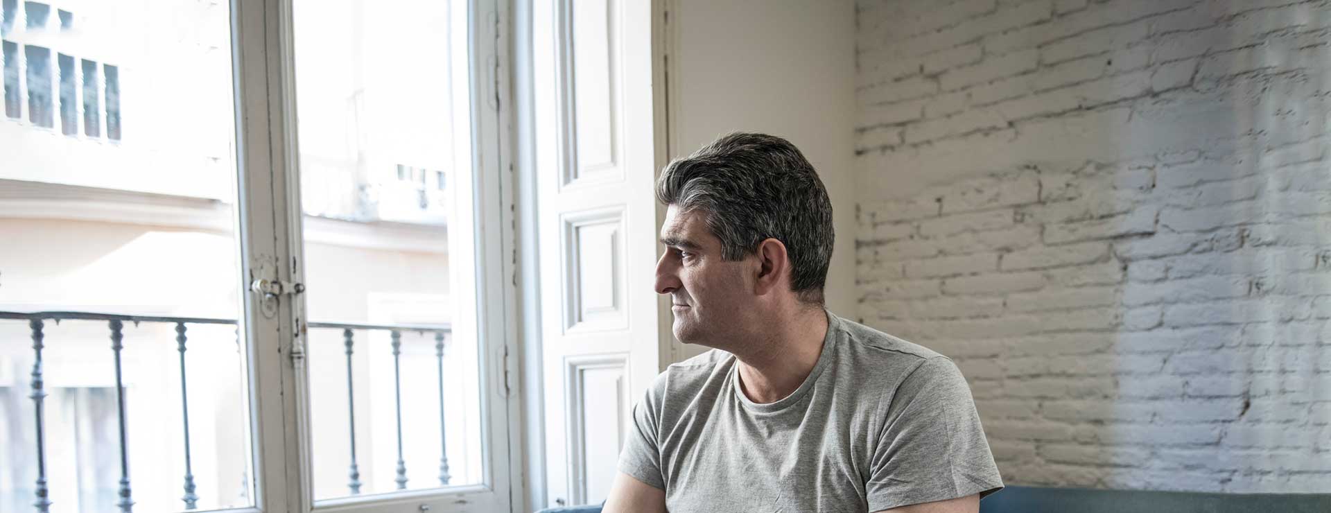 A middle-aged man looks pensively out the window.