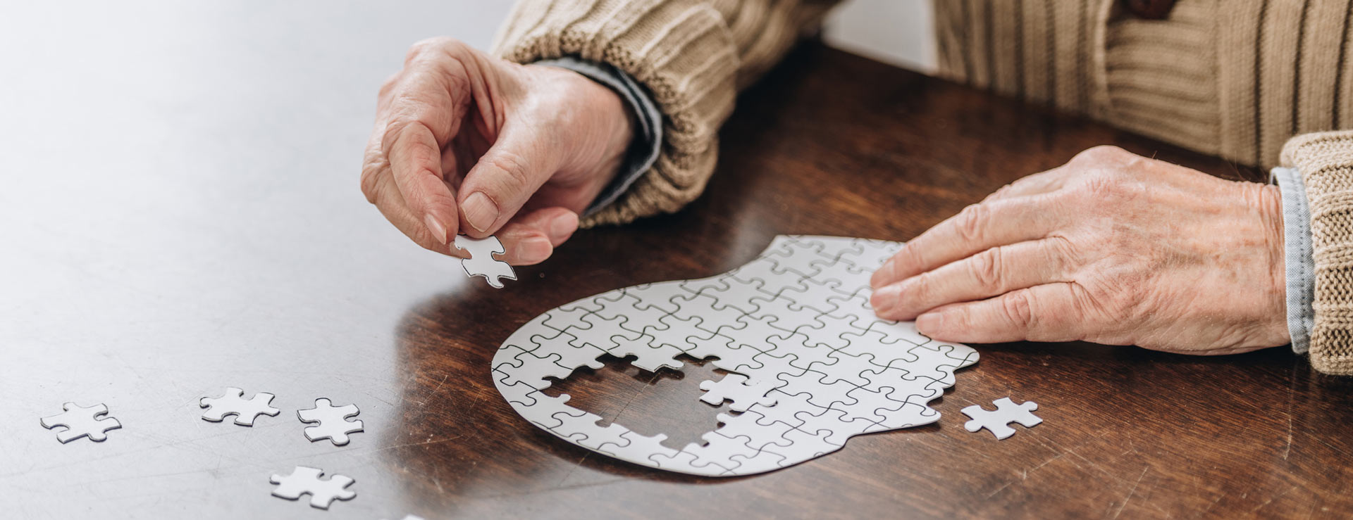 Elderly person putting together a puzzle shaped like a head
