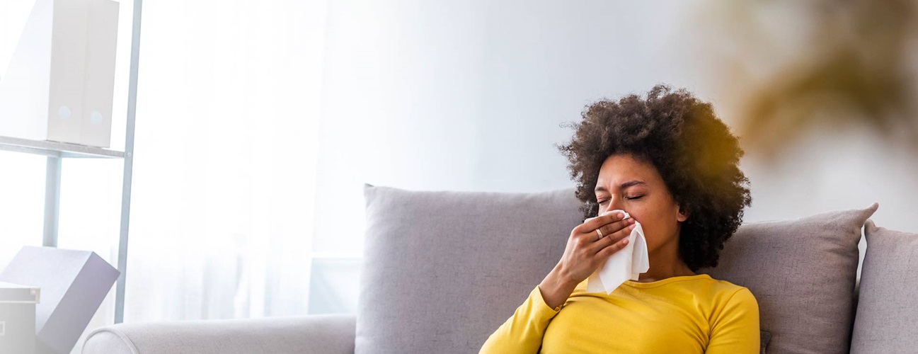 Woman with the flu sneezing into a tissue