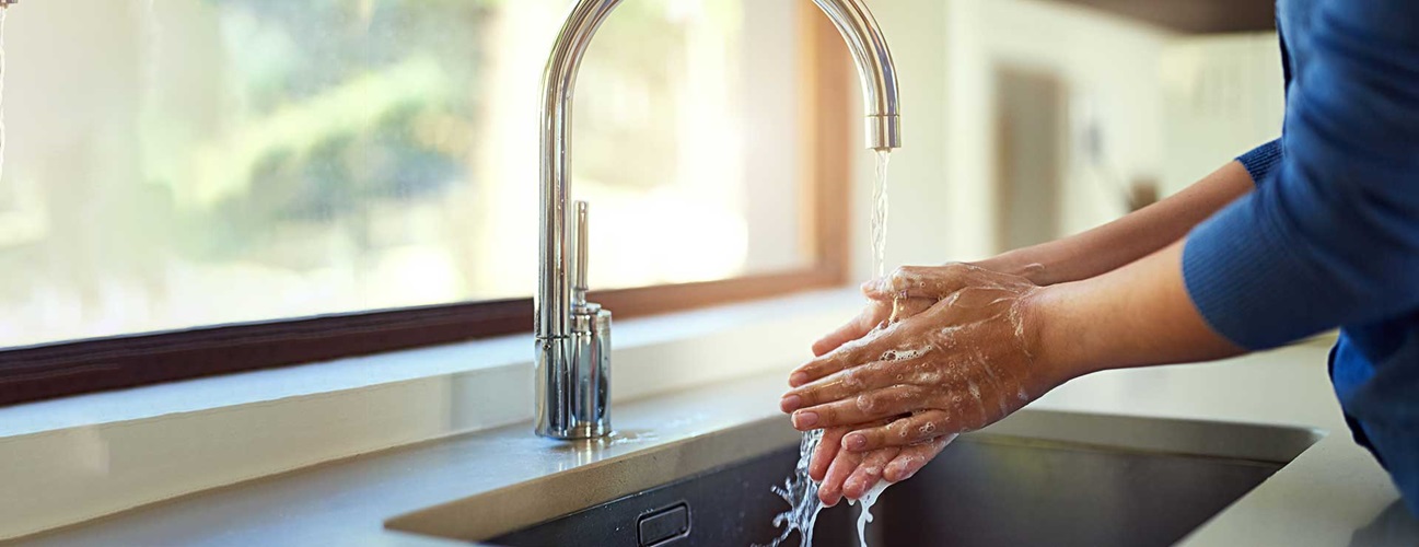 Woman washing her hands in her kitchen sink