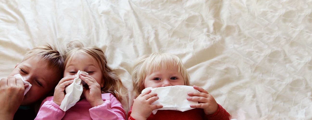 Children blow their noses, sick in bed.