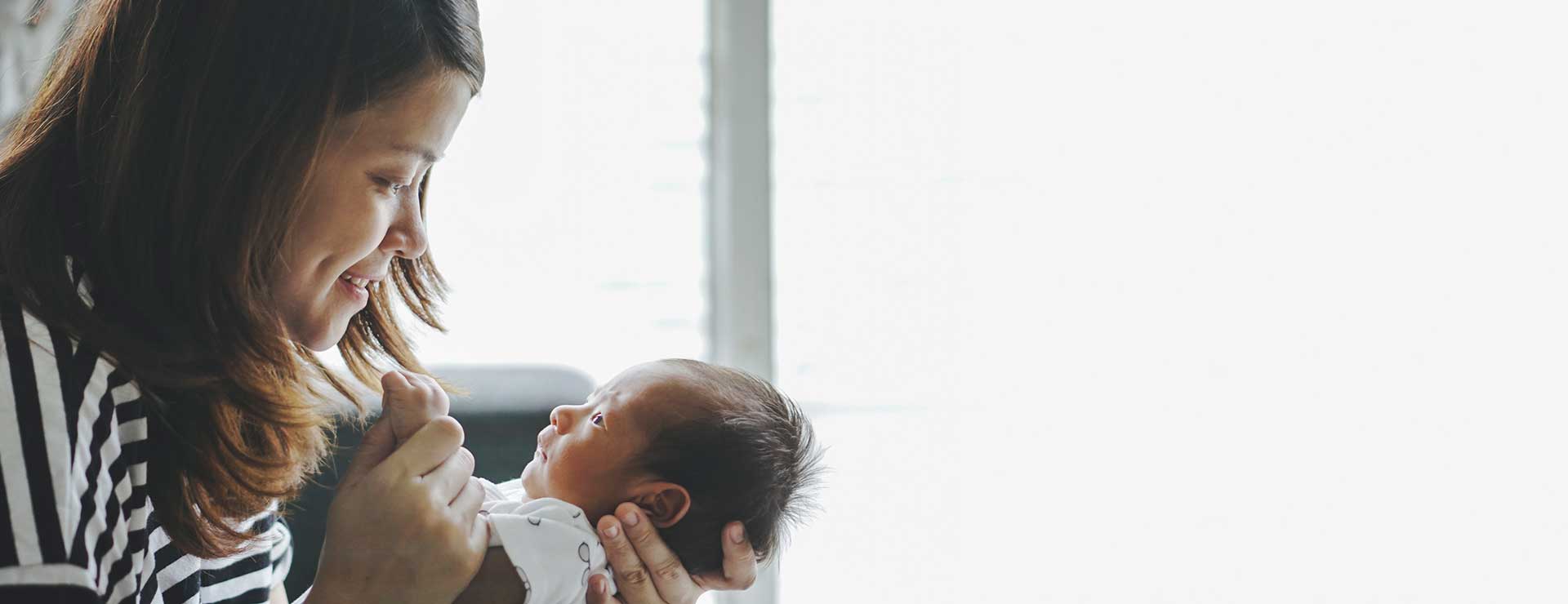 A mother smiles at her newborn baby.