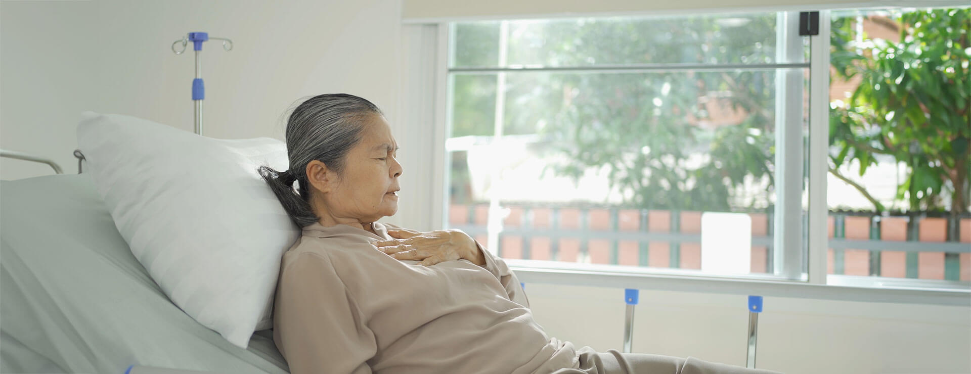 an older woman in a bed holds her chest
