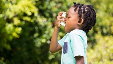 Boy using asthma inhaler outside