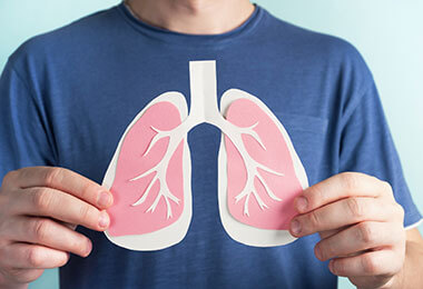 a man holds a paper depiction of lungs