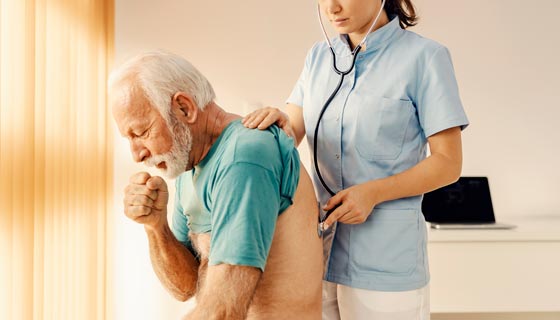 Older patient coughing and getting his lungs checked by a doctor