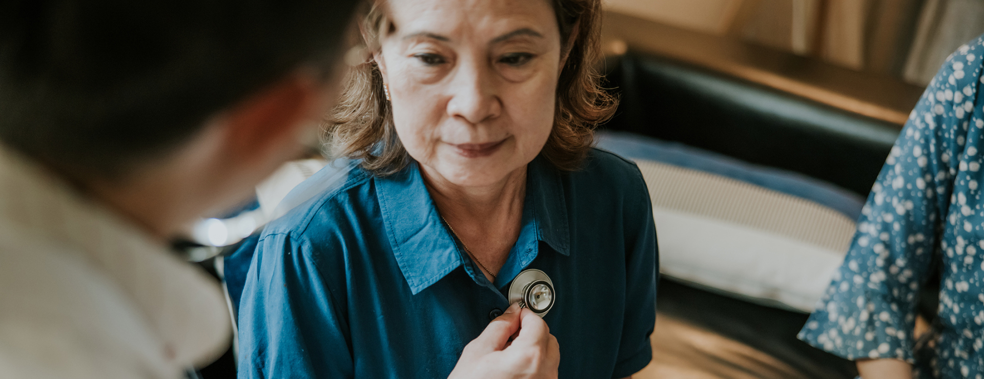 A woman having her lungs listened to by a doctor
