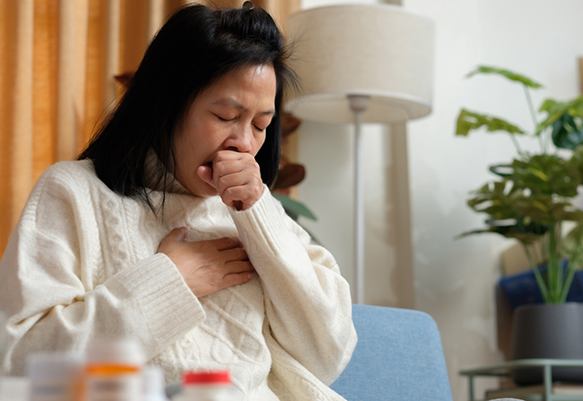 A woman coughing and holding her chest